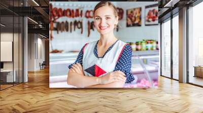 Proud woman selling meat and sausages in butcher shop Wall mural