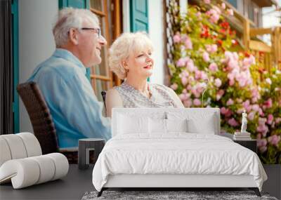 Senior couple enjoying their coffee on porch in front of their house Wall mural