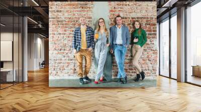 Team of people in startup company standing on brick wall in informal fashion Wall mural