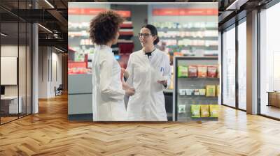 two friendly female colleagues talking about medicines and prescriptions while working together as p Wall mural