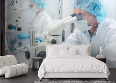 Two lab technicians or scientists working in laboratory looking thru microscopes  Wall mural