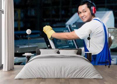 Worker entering data in CNC machine at factory floor to get the production going Wall mural