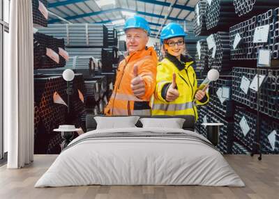 Worker team in warehouse of a steel trade showing thumbs up Wall mural