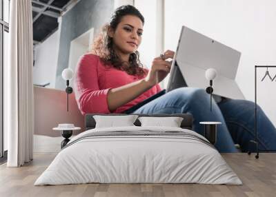 Young freelancer sitting in armchair in agency working on laptop PC Wall mural