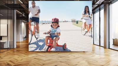 Cycling, bonding and family on the promenade with a bike for summer fitness, fun and quality time in Thailand. Learning, happiness and girl child with bicycle, mother and father at a park by the sea Wall mural