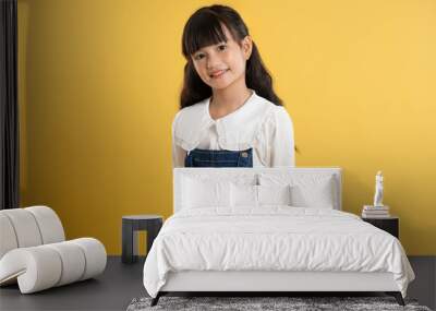 Portrait of asian kid girl posing on yellow background Wall mural