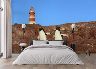 2 rockhopper penguins  with a lighthouse in the backroung, Isla Pingino - Patagonia Argentina  Wall mural