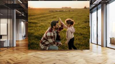 Happy Caucasian family on holiday vacation. Smiling father and little daughter holding hands and walking together on the meadow field. Parent with cute child girl relax and enjoy an outdoor lifestyle. Wall mural