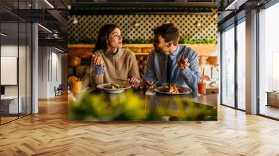 Happy young woman eating lunch with her boyfriend in a restaurant Wall mural