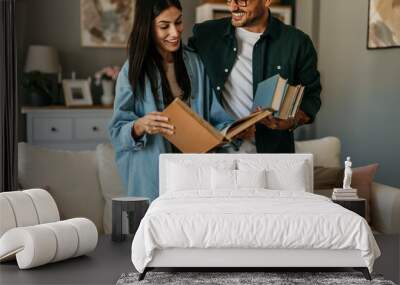 Loving mid aged couple holding and taking out books, unpacking during relocation into a new house. Wall mural