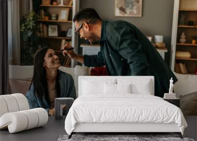 Playful man having fun with his wife during a writing activity on a cardboard box during a packing at their living room Wall mural