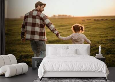 Rear view of a family on holiday vacation. Smiling father and little daughter holding hands and walking together on the meadow field. Parent with cute child girl relax and enjoy an outdoor lifestyle. Wall mural