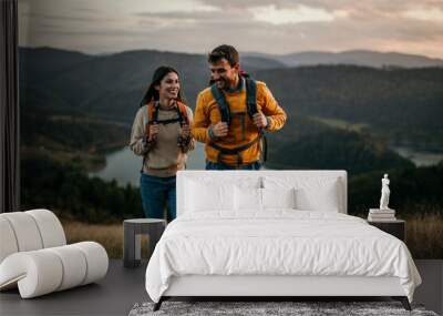 Shot of a couple going for a hike up the mountain, lake in the background Wall mural