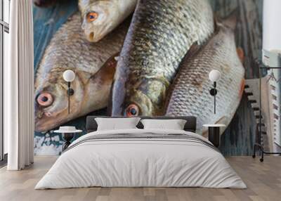 Freshly caught fish on a wooden table and a knife for cleaning o Wall mural