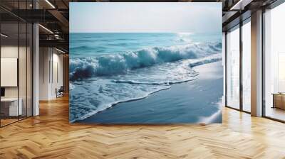 Blue ocean wave crashing gently on the sandy beach under the bright sunlight on a serene summer day Wall mural