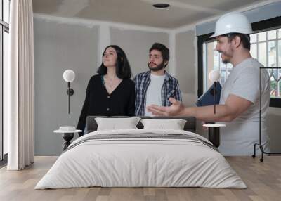 Architect shows new apartment in construction to young couple interested in buy. Wall mural