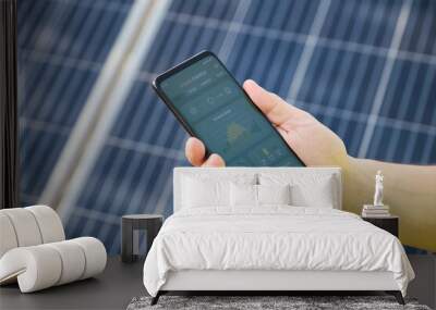 Hands checking solar power generation in a smartphone app. Wall mural