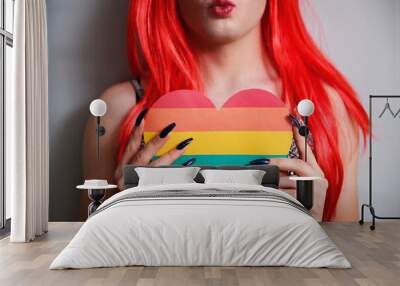 Kissy face unrecognizable transgender person holding a rainbow flag heart. Wall mural