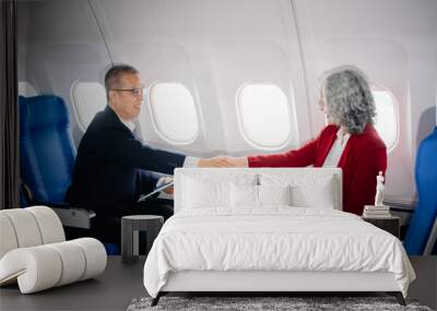 Business meeting in airplane, asian Mature businessman in private jet is talking with Mature female colleague and documents, business people flying Wall mural