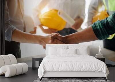 Engineers or architecture shaking hands at construction site for architectural project, holding safety helmet on their hands. Wall mural