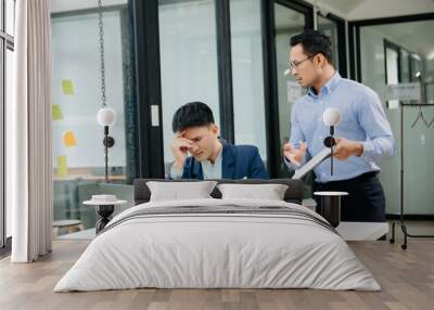 Furious two Asian businesspeople arguing strongly after making a mistake at work in modern office Wall mural