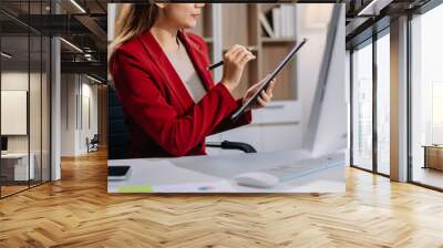 Young beautiful woman typing on tablet and laptop while sitting at the working white table in modern office Wall mural