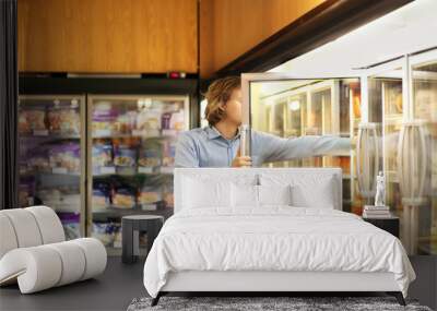 Man choosing frozen food from a supermarket freezer Wall mural