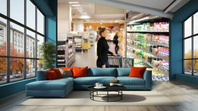 Woman choosing a dairy products at supermarket Wall mural