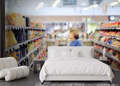 Young man shopping in supermarket, reading product information Wall mural