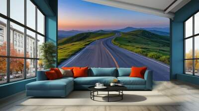 A winding road with lush green grass under sunset sky Wall mural