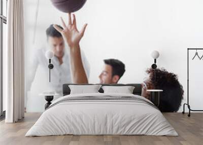 He cant wait to get to basketball. A young man playing with a basketball while sitting in the office. Wall mural