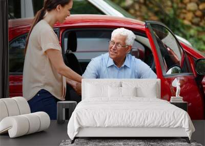 Let me help you out of the car. Shot of a woman helping her senior father out of the car. Wall mural