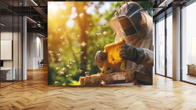 A beekeeper or apiarist wearing a bee suit, inspecting a honeycomb while bees are buzzing around it and a beehive box. harvesting honey concept. Wall mural