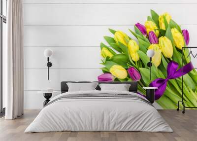 bouquet of yellow and pink tulips with purple ribbon on white wooden background. top view, copy spac Wall mural