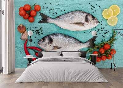 Raw dorado fish, cherry tomatoes, garlic and lemon on blue background. Top view Wall mural