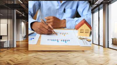 Asian businessman uses pen to analyze graph, real estate market, laptop computer  and borrowed paper in the office Wall mural