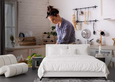 Young and beautiful housewife woman cooking in a white kitchen Wall mural