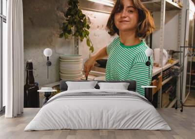 happy young woman cooking spaghetti with pesto hands holding pasta bunch putting into the frying pan Wall mural