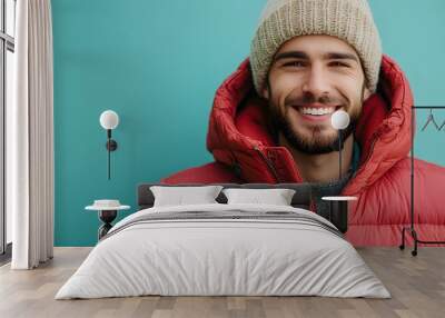 Cheerful young man in beanie and puffer jacket Wall mural