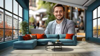 Smiling businessman working on laptop in outdoor cafe, concept of remote work, entrepreneurship, and modern business lifestyle
 Wall mural