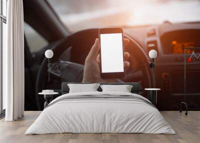 Close-up, hand of man holding smartphone with mockup on background of car dashboard. Wall mural