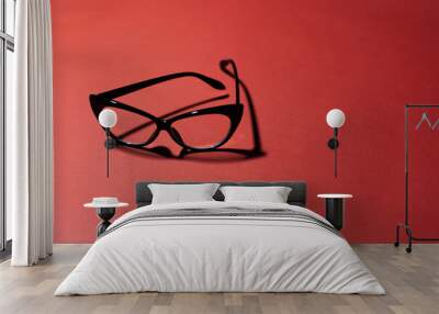 Close-up of black cat eyeglasses on studio background of dark red color with copy space. Wall mural