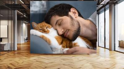 Sleeping young man and red white cat. Wall mural