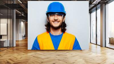 Studio portrait of young happy man, construction worker engineer wearing safety equipment on background of grey textured wall. Panoramic banner view. Wall mural