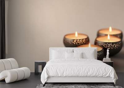 Four candles burning in perforated holders, arranged together on a beige background, creating a warm and serene atmosphere. Wall mural