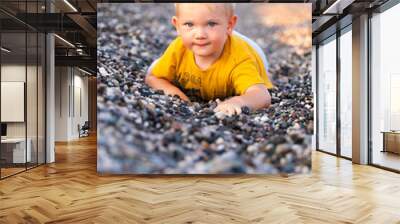 The boy lies on a pebble beach and looks at the sea Wall mural