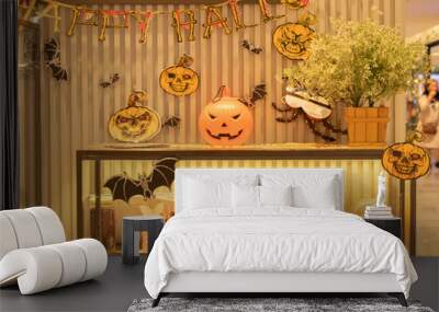 Big pumpkin with carved funny glowing face standing on background of Halloween decor. Halloween Jack o Lantern Pumpkin with a spooky face.  Wall mural