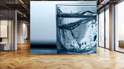 Crystal-clear water cascading into a glass with intricate droplets and splashes vividly visible against a white background Stock Photo with copy space Wall mural