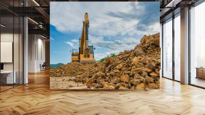 Backhoe is working on pile of stones at construction site Wall mural