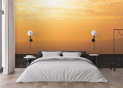 Silhouette of a fisherman on a boat in the sea or lake against the backdrop of water and a sunrise or sunset. Wall mural